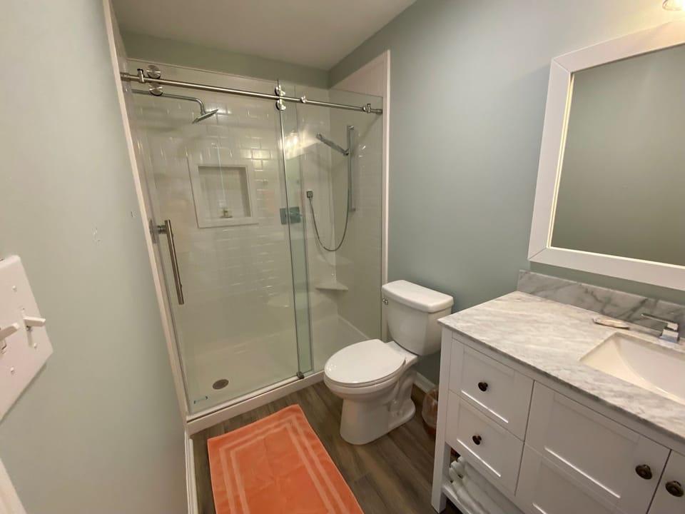 Step into your beautifully renovated bathroom with a spacious walk-in shower, elegant marble vanity, and soothing sage green walls for ultimate relaxation.