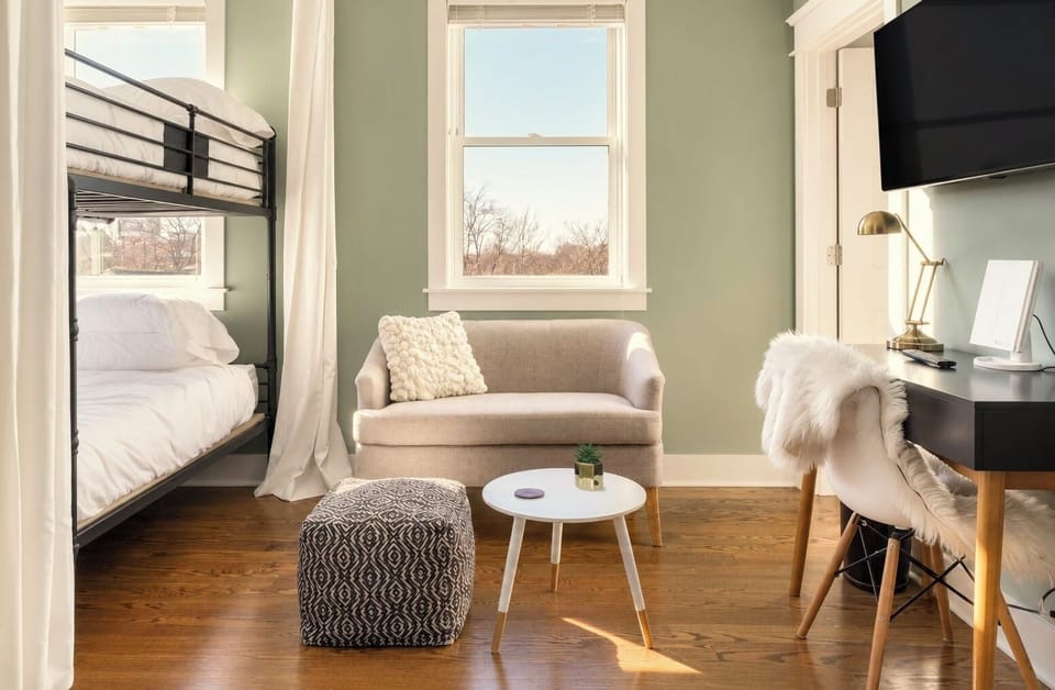 Bright bunk room with cozy lounge area, desk setup, and abundant natural light