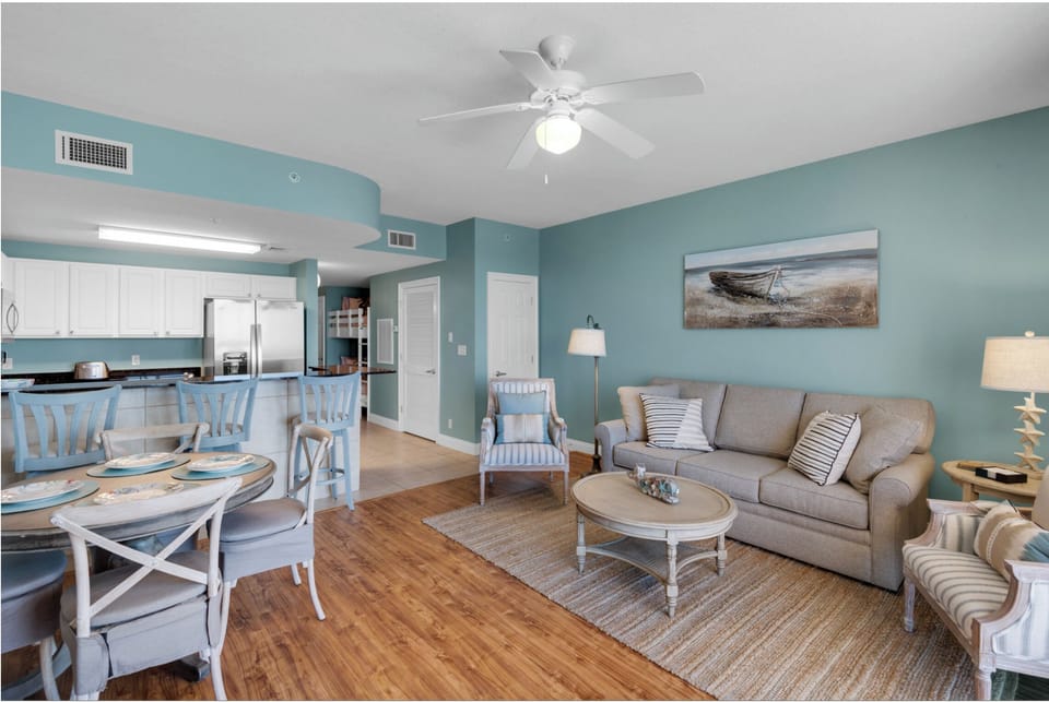 Relax in your coastal-inspired living space with soft blues, comfortable seating, and an open kitchen perfect for preparing meals together.