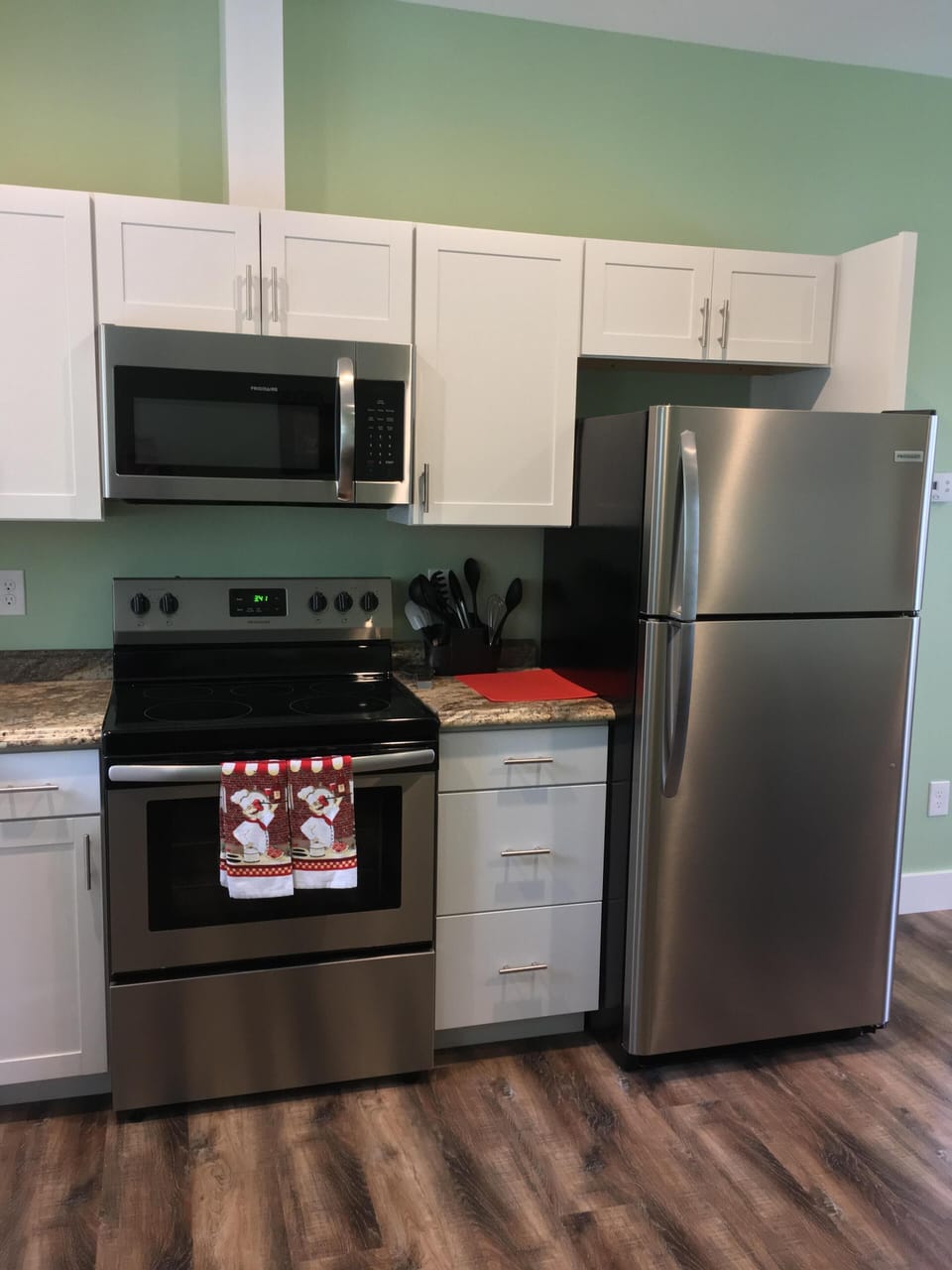 Full sized refrigerator with cabinets stocked with cooking supplies, dishes, etc