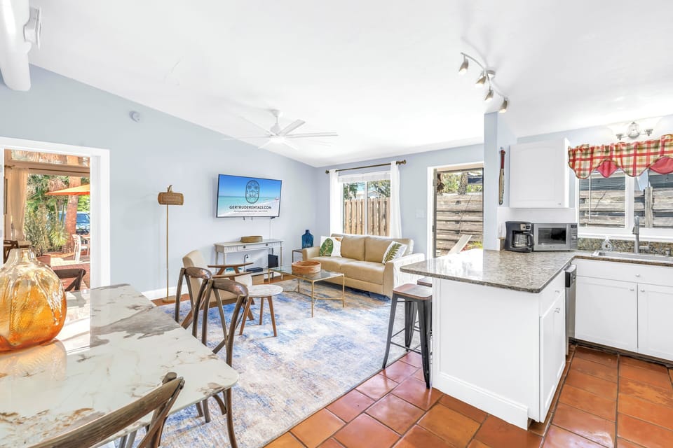 Open living and dining area with TV, kitchen and patios on two sides.