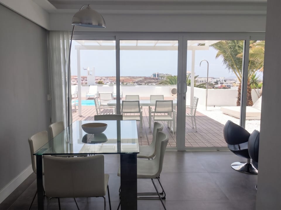 Unforgettable dinners: elegant indoor dining room with glass table and panoramic views of the terrace.