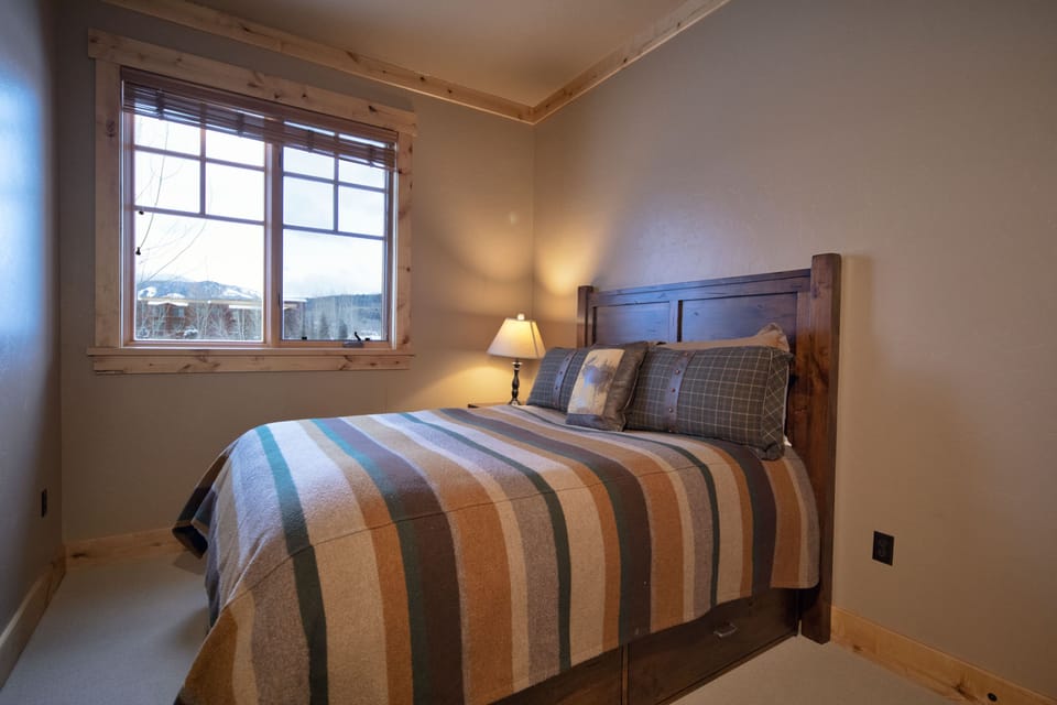 Wake up to breathtaking mountain views from your cozy bedroom, where warm wood accents and soft lighting create the perfect retreat after a day of adventure.