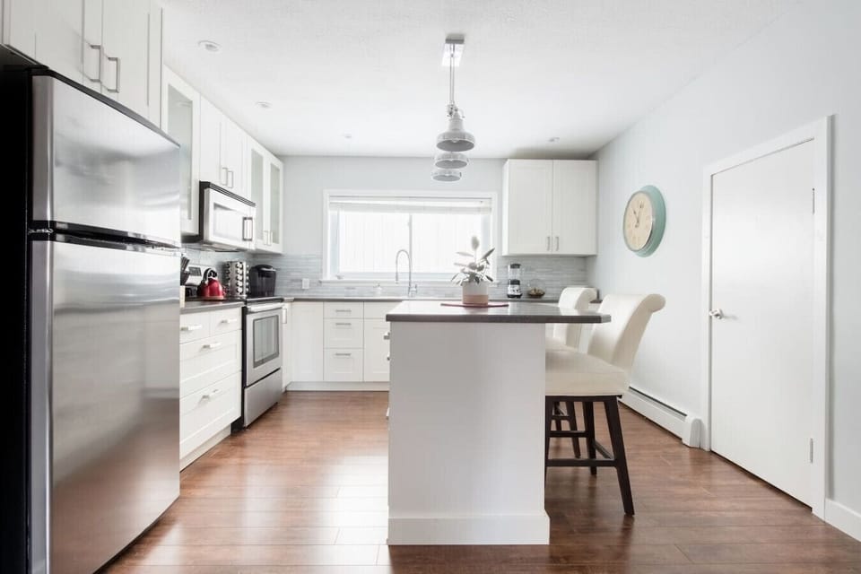 Bright, modern kitchen with stainless steel appliances, spacious island seating, and beautiful wood floors. This fully equipped kitchen is perfect for cooking, dining, and enjoying a comfortable, stylish stay.
