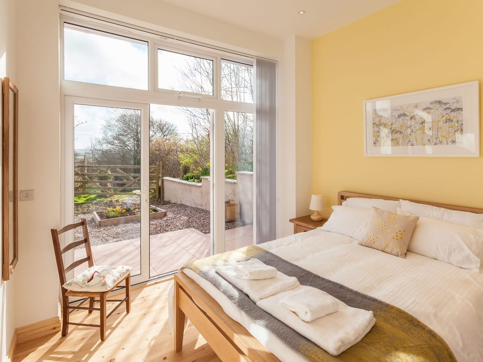 Relaxing bedroom with French doors leading to terrace | The Red Barn, Braunton, near Barnstaple