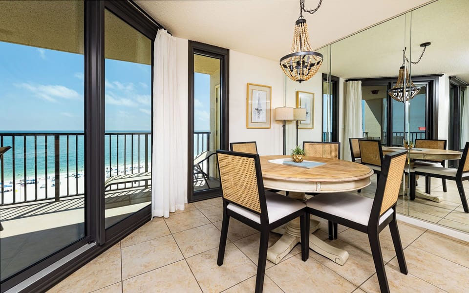 Relax at your round dining table with a refreshing drink, soaking in coastal views through the floor-to-ceiling windows