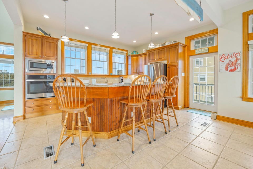 Your spacious kitchen features warm wood cabinetry, granite countertops, and a charming breakfast bar where you can enjoy morning coffee with natural light streaming through tall windows.