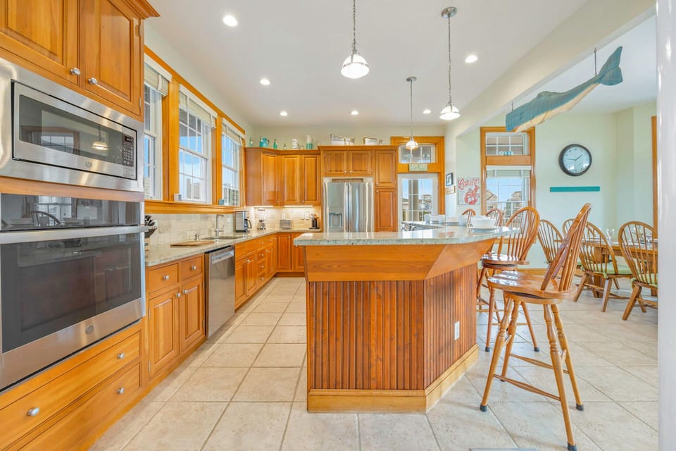 You'll love preparing meals in this spacious, well-equipped kitchen featuring warm wood cabinetry, granite countertops, and modern stainless steel appliances.