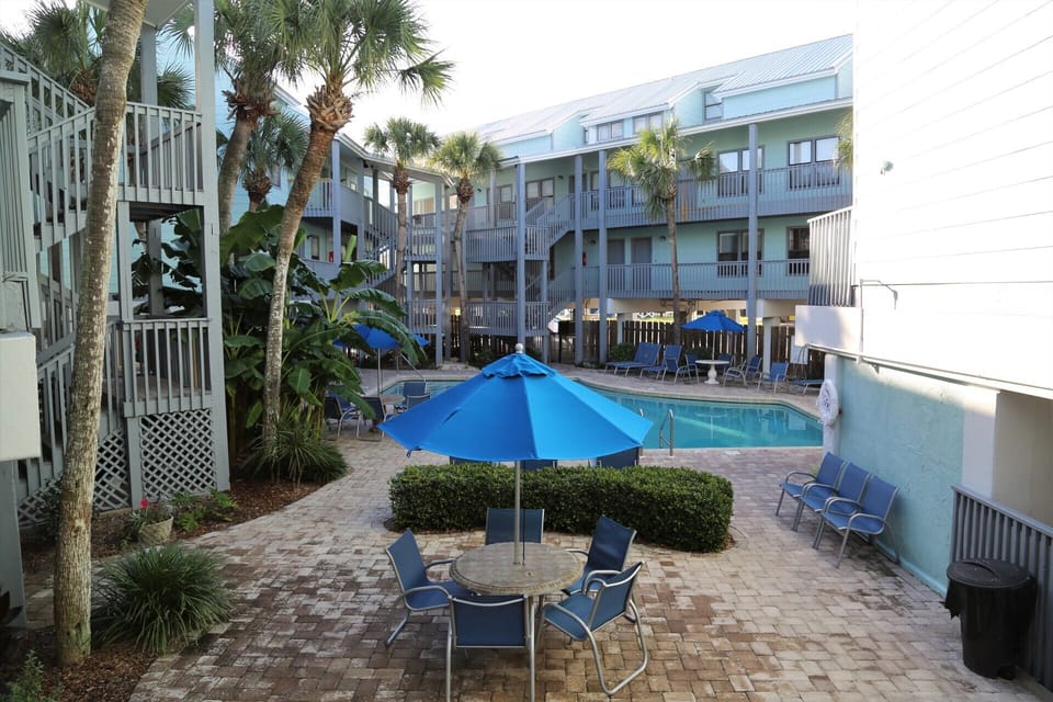 Tropical pool deck with picnic tables & BBQ.