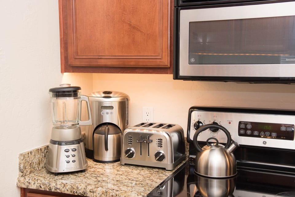 Fully stocked kitchen with coffee pot, tea kettle, blender, toaster and cookware