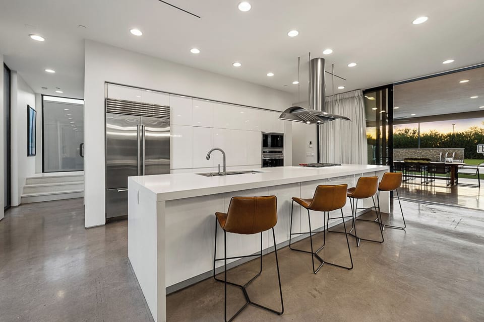 Gleaming white island, steel hood, leather stools, cook in style