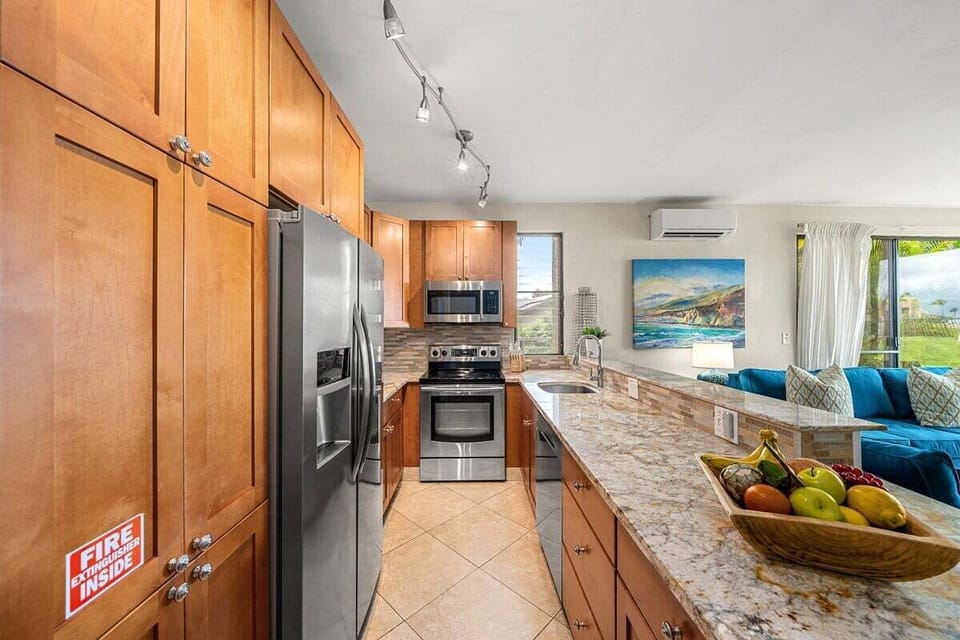 In the kitchen, granite counters and fruit bowl brighten wood and steel, artwork tying the space to the sea.