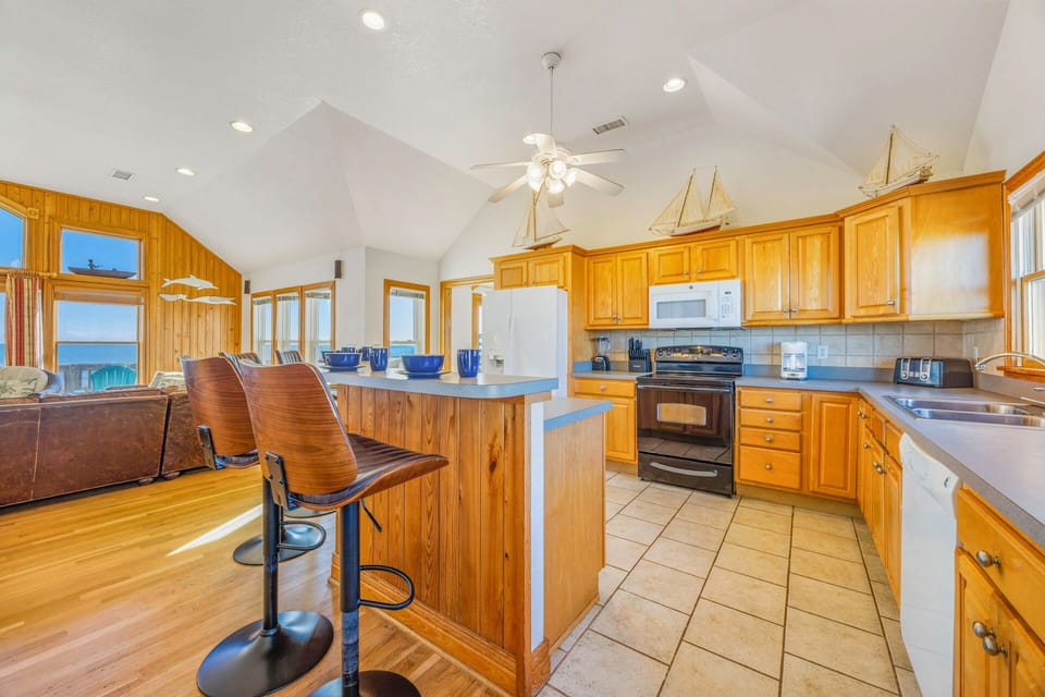 Your spacious kitchen features warm wood cabinets, modern appliances, and a breakfast bar where you can sip coffee while enjoying ocean views.
