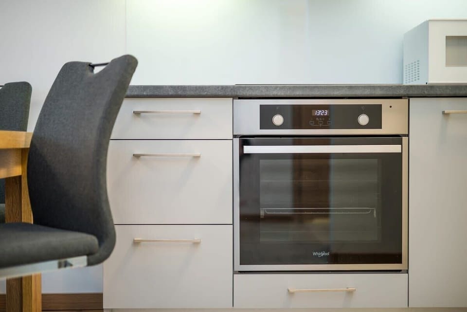 A sleek kitchen featuring white cabinetry, stainless steel appliances, and an organized countertop, offering a clean and functional cooking area.