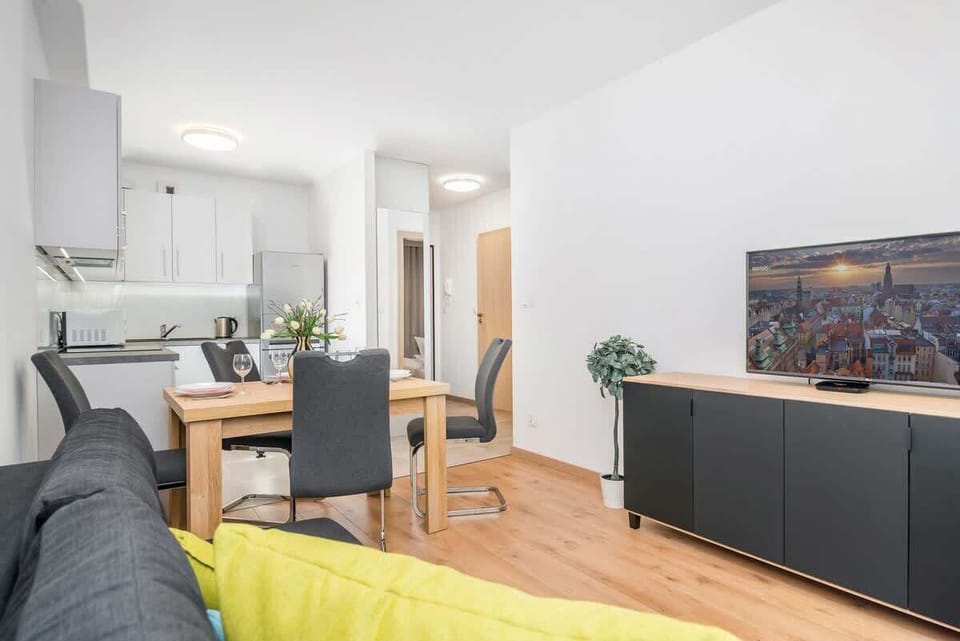 Another view of the spacious living room, featuring a gray sofa, large windows, and a stylish TV stand, blending comfort and modern design.
