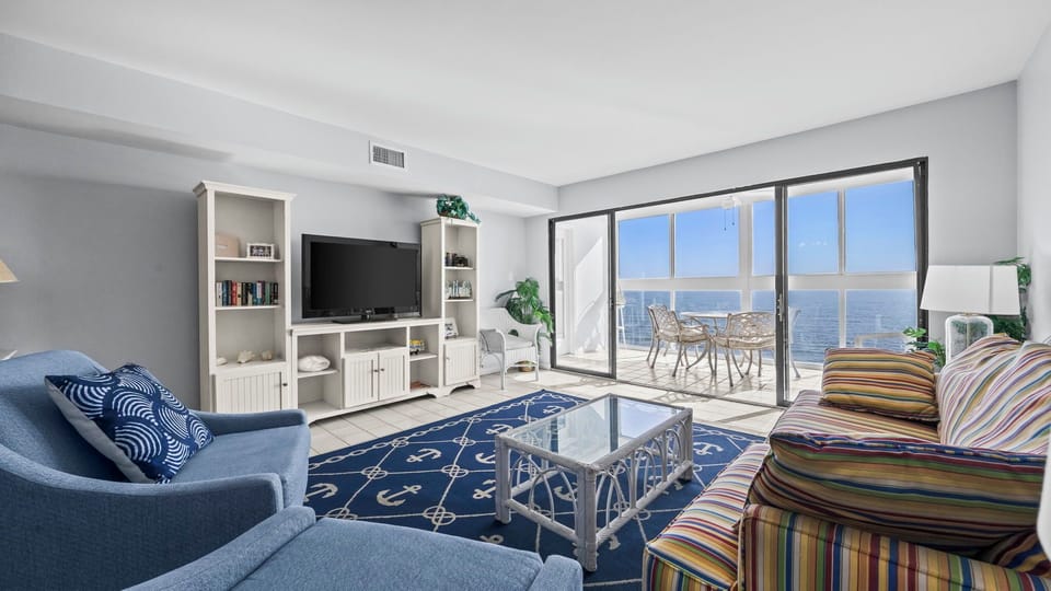 Edgewater West 95 - Bright and spacious living area with a TV and a beautiful Gulf view backdrop.