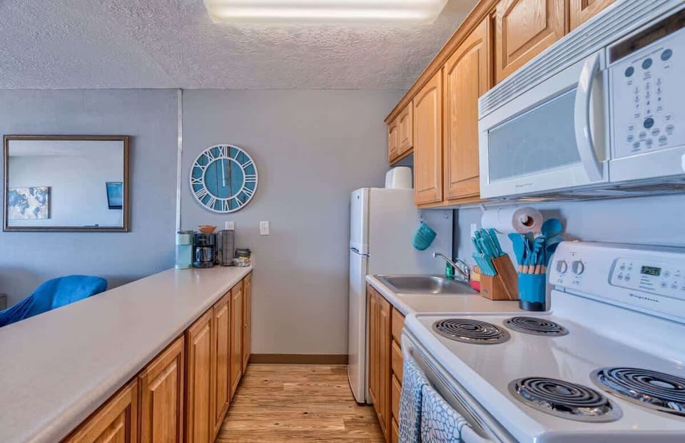 The condo has a full kitchen with a fridge, microwave, and stove/oven