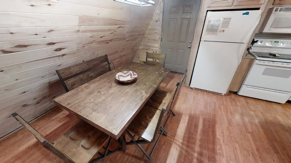 Gather around this rustic wooden dining table in your cozy kitchen, perfect for morning coffee or family meals. The space blends warmth and function with natural wood finishes and full appliances.
