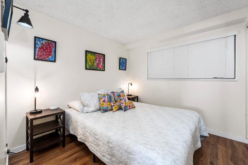 Unwind in your bright bedroom featuring vibrant artwork, cozy reading lamps, and soft linens—your perfect retreat after exploring the city.