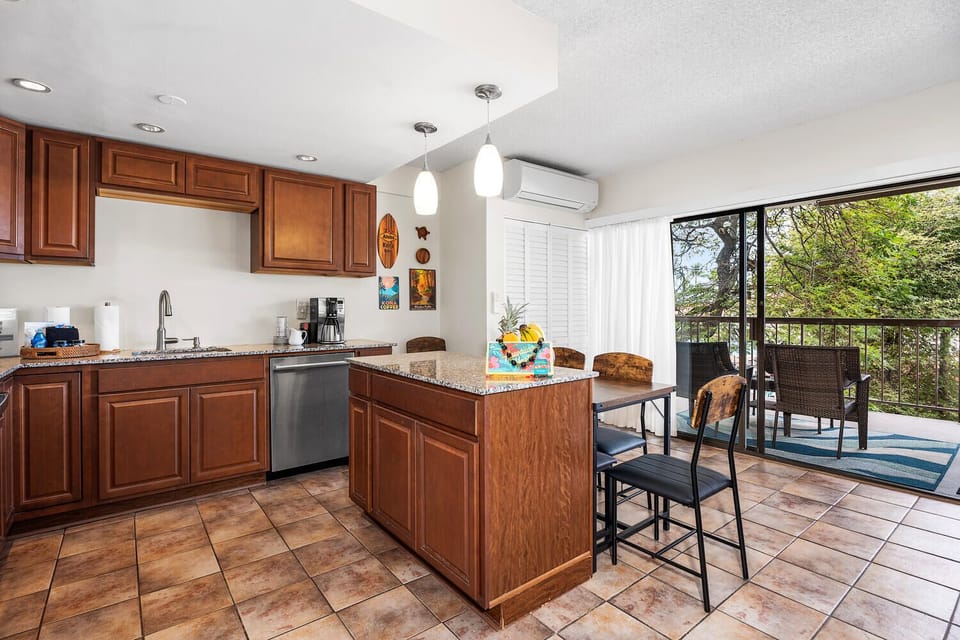 Your open kitchen features granite countertops, rich wood cabinetry, and flows seamlessly to your private lanai with garden views.