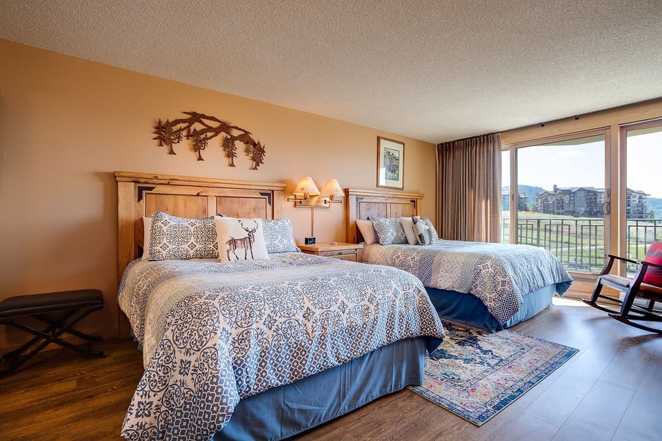 Unwind in this inviting bedroom with two plush queen beds, mountain-themed décor, and your own private balcony overlooking sweeping mountain and valley views.