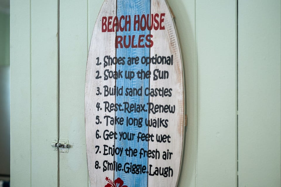A charming surfboard sign sets the perfect beach house mood with playful rules for relaxation.
