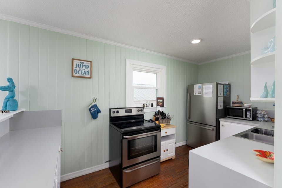 Your coastal kitchen awaits with ocean-themed charm, full appliances, and soothing seafoam walls perfect for preparing memorable vacation meals.