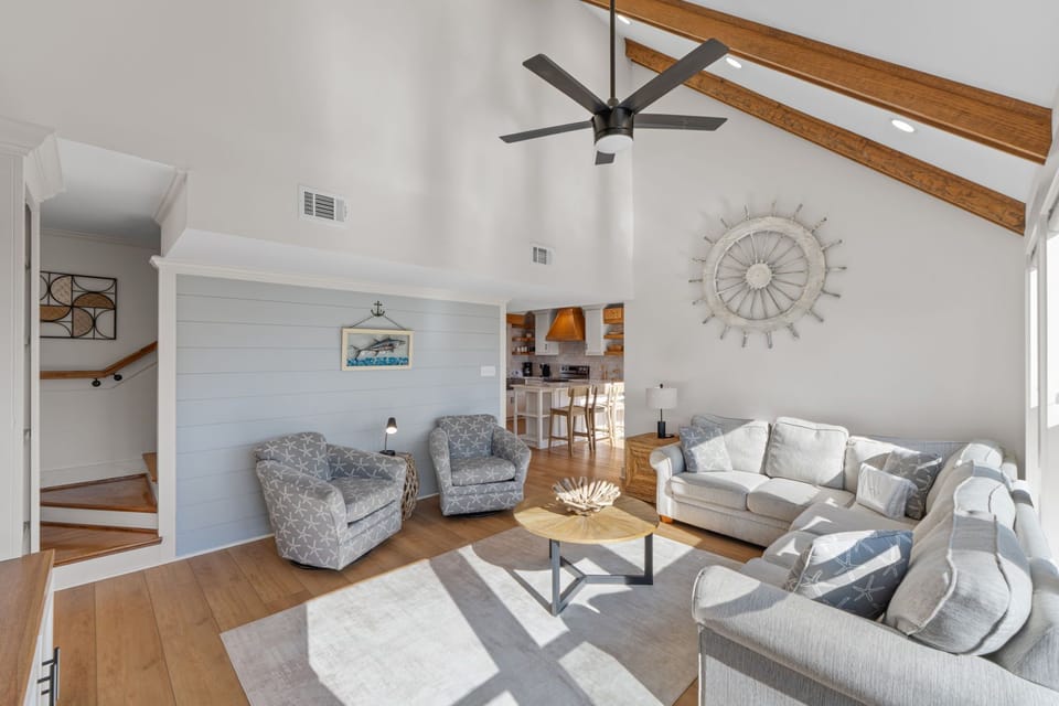 Your open-concept living space features vaulted ceilings, warm wood beams, and coastal-inspired decor creating a bright, airy retreat.
