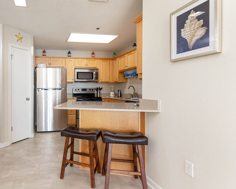 Bright wooden cabinetry complements the kitchen's sleek appliances and inviting breakfast bar with stylish seating