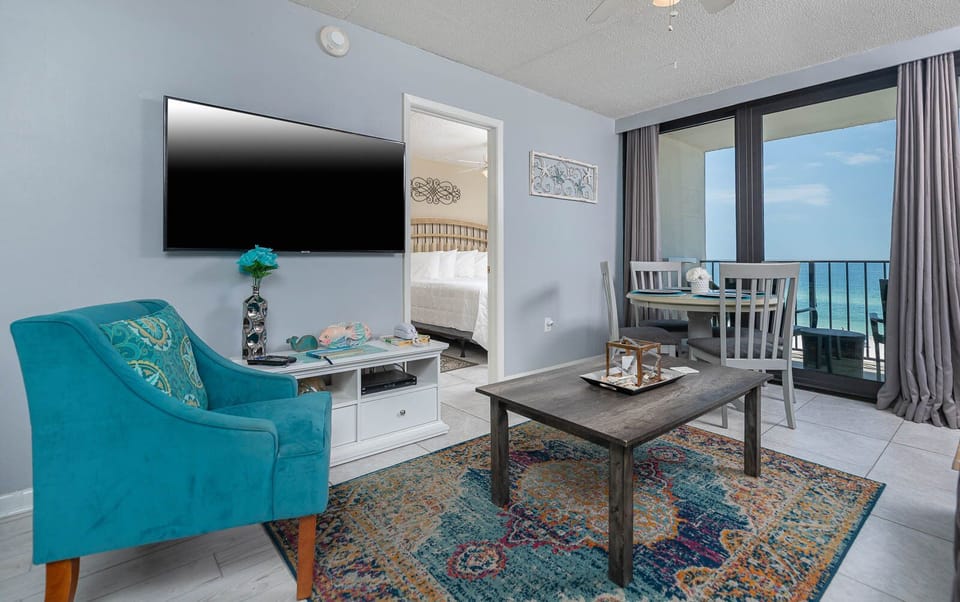This inviting condo features a vibrant chair, a flat-screen TV, and stunning beachfront views through large windows