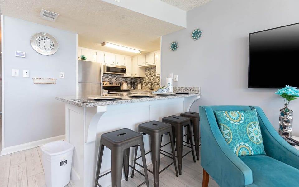 This modern kitchen features sleek stainless appliances and a cozy bar area with seating, perfect for casual dining