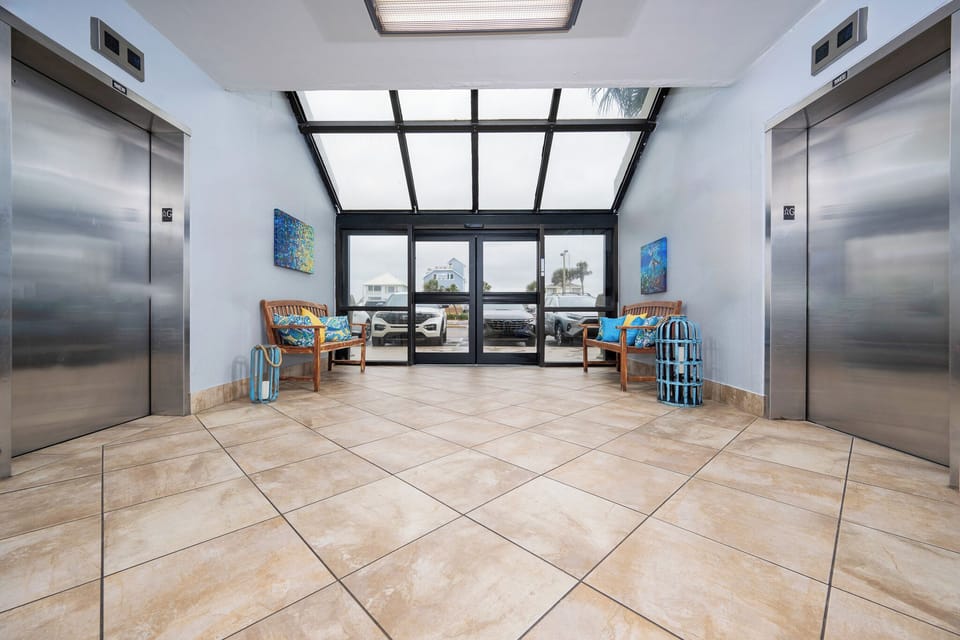 Step into a welcoming lobby area with stylish seating and easy elevator access, just moments from the beach