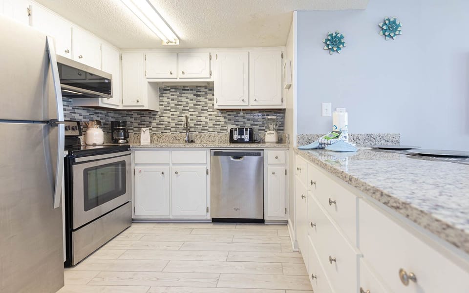 The kitchen features stainless appliances, granite countertops, and cheerful coastal decor for a delightful experience
