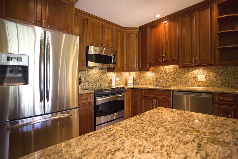 A fully equipped kitchen with gleaming granite countertops, rich wood cabinetry, and stainless steel appliances awaits your culinary creations and memorable meals.