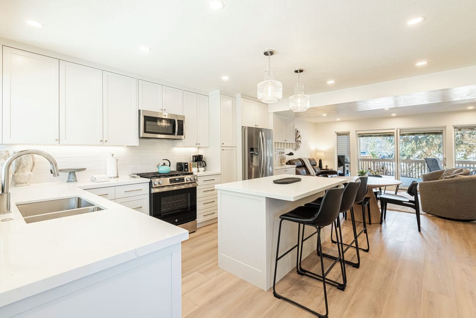 modern kitchen features white shaker cabinets, quartz countertops, stainless steel appliances, and a spacious island with seating.