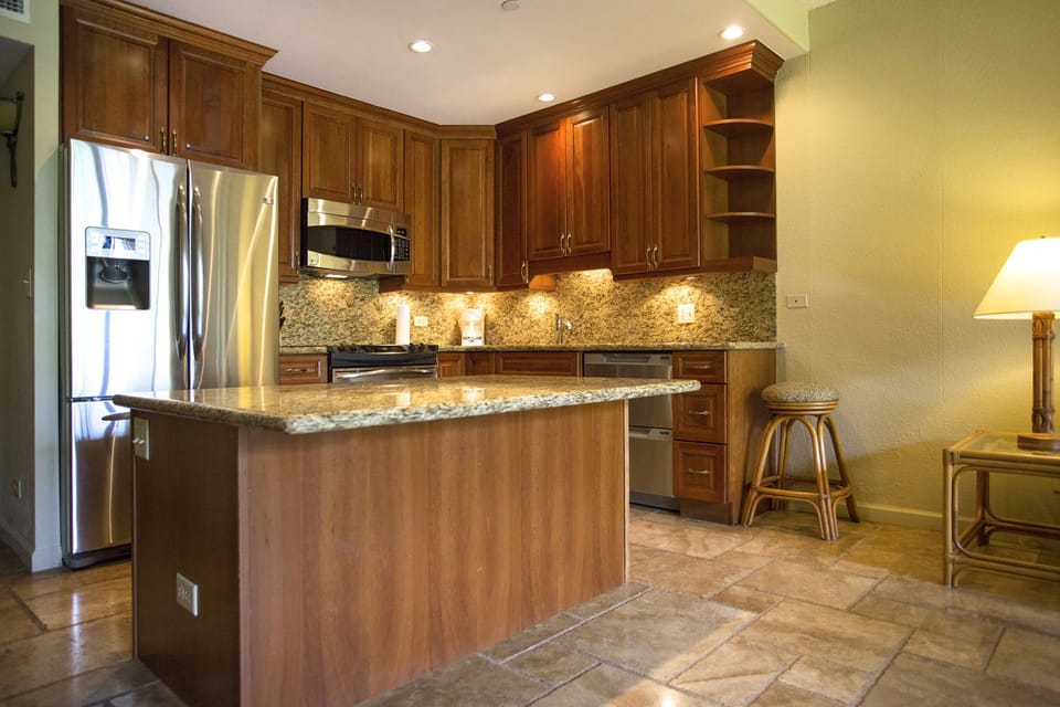 Your fully equipped kitchen features rich wood cabinetry, granite countertops, stainless steel appliances, and warm under-cabinet lighting—perfect for preparing home-cooked meals during your stay.
