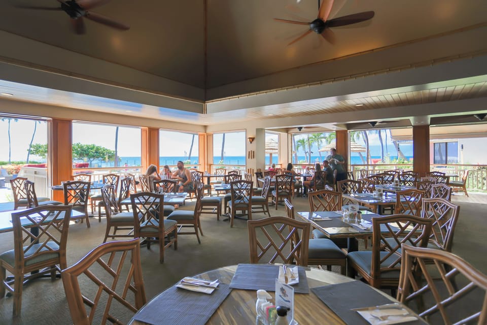 A welcoming oceanfront dining space where you'll enjoy meals with stunning sea views through large windows, ceiling fans keeping the air fresh and light as you dine.