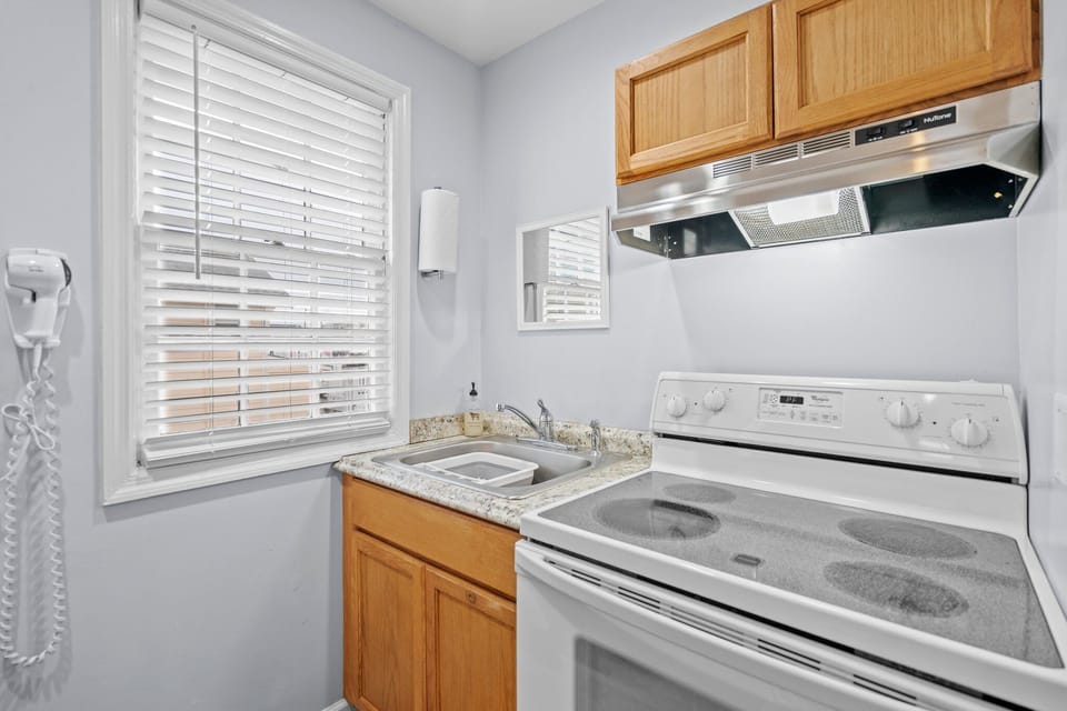 Your compact kitchen features everything you need - granite counters, full appliances, and warm wood cabinets for preparing meals at home.