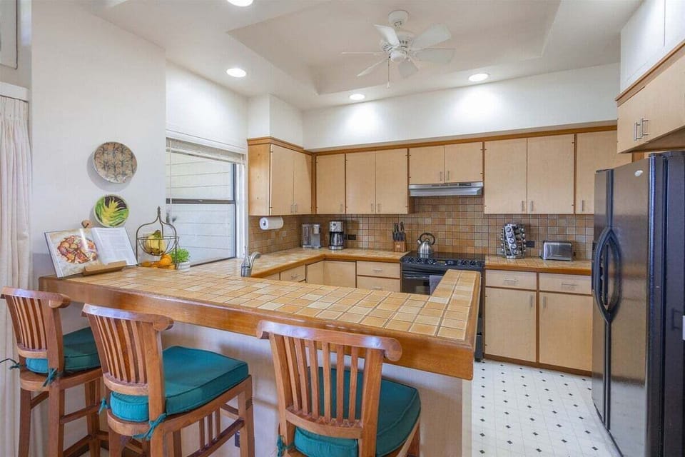 Open kitchen seamlessly connected to dining and living areas, complete with a breakfast bar with seating for three
