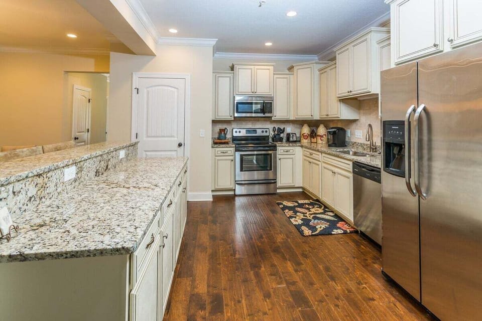 White kitchen with granite island and stainless appliances