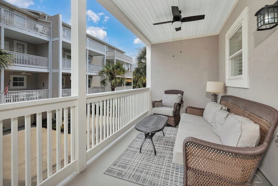 Covered balcony with wicker seating and neighborhood view
