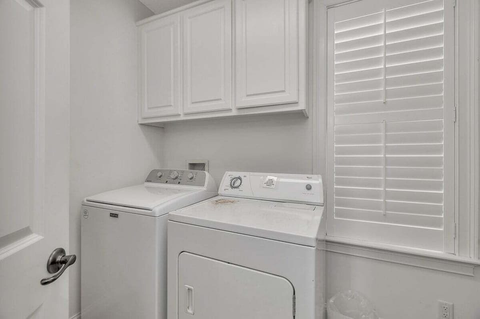 Laundry room with washer, dryer, and white cabinetry