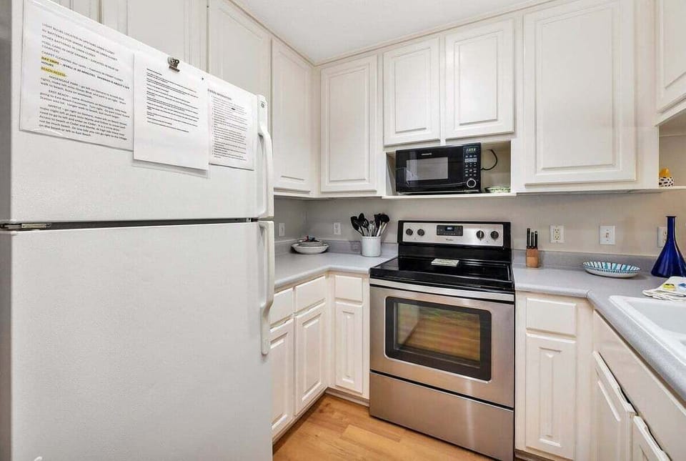 White kitchen with stainless appliances and wood floors