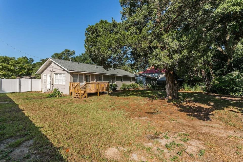 Property exterior with large yard, deck, and large tree