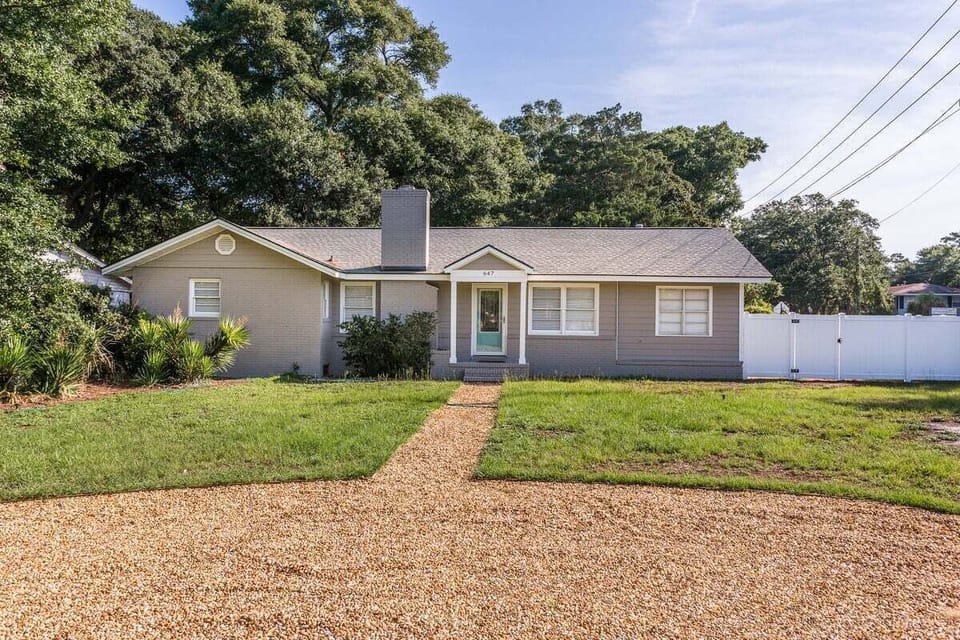 Property exterior with gravel path, green lawn, and chimney