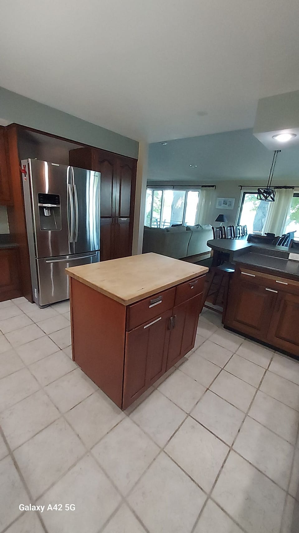 Kitchen view showing fridge, dining table, living room and windows facing bay.