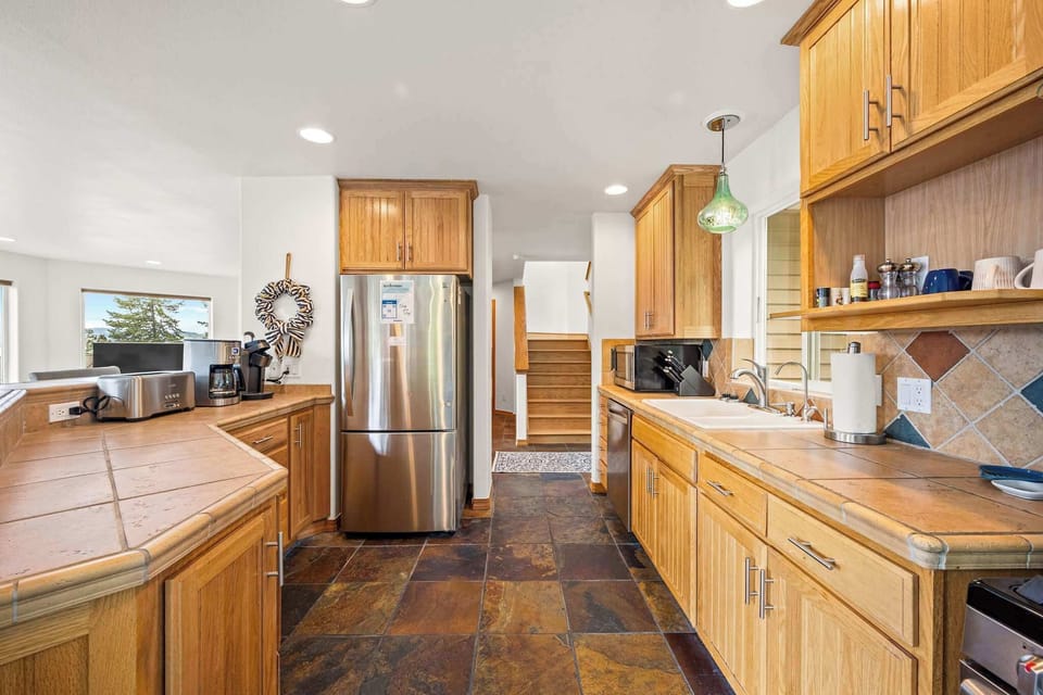 Warm wood cabinetry and spacious countertops create your perfect cooking sanctuary, with modern appliances ready for memorable meals.