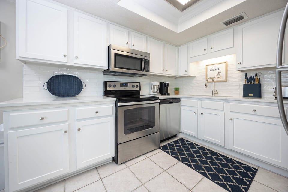 This kitchen features stainless appliances, white cabinetry, and a cozy atmosphere, perfect for your culinary adventures