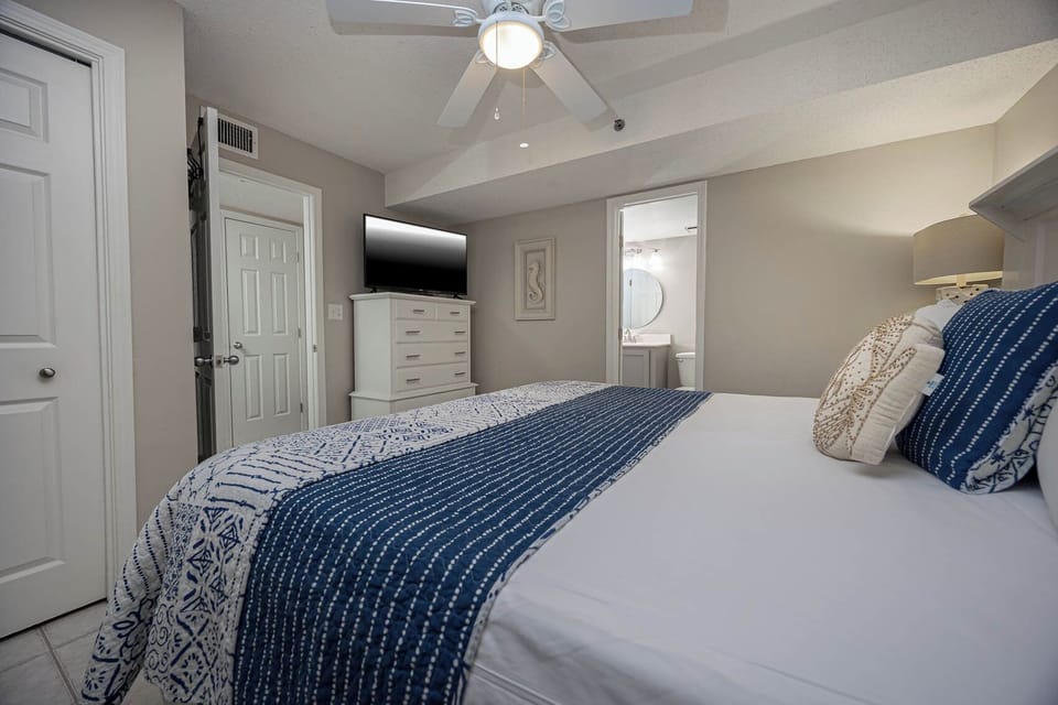 This cozy bedroom features a stylish decor, a flat-screen TV, and an en-suite bathroom with a round mirror