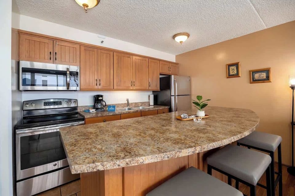 Whip up your favorite meals in this fully equipped, modern kitchen, featuring stainless steel appliances, ample counter space, and a breakfast bar perfect for casual dining.
